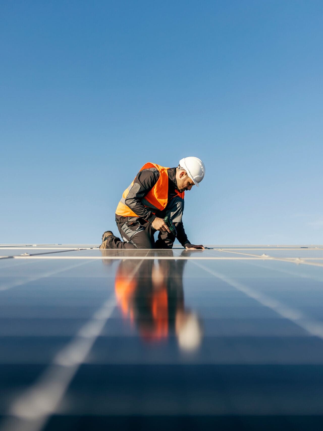 A handyman on the rooftop installing solar panels.
